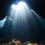 a sunbeam shines through a cave in the ocean